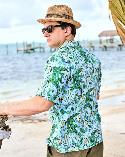 Three-quarter back view of the Blue Lagoon alligator-print camp shirt worn at a beach