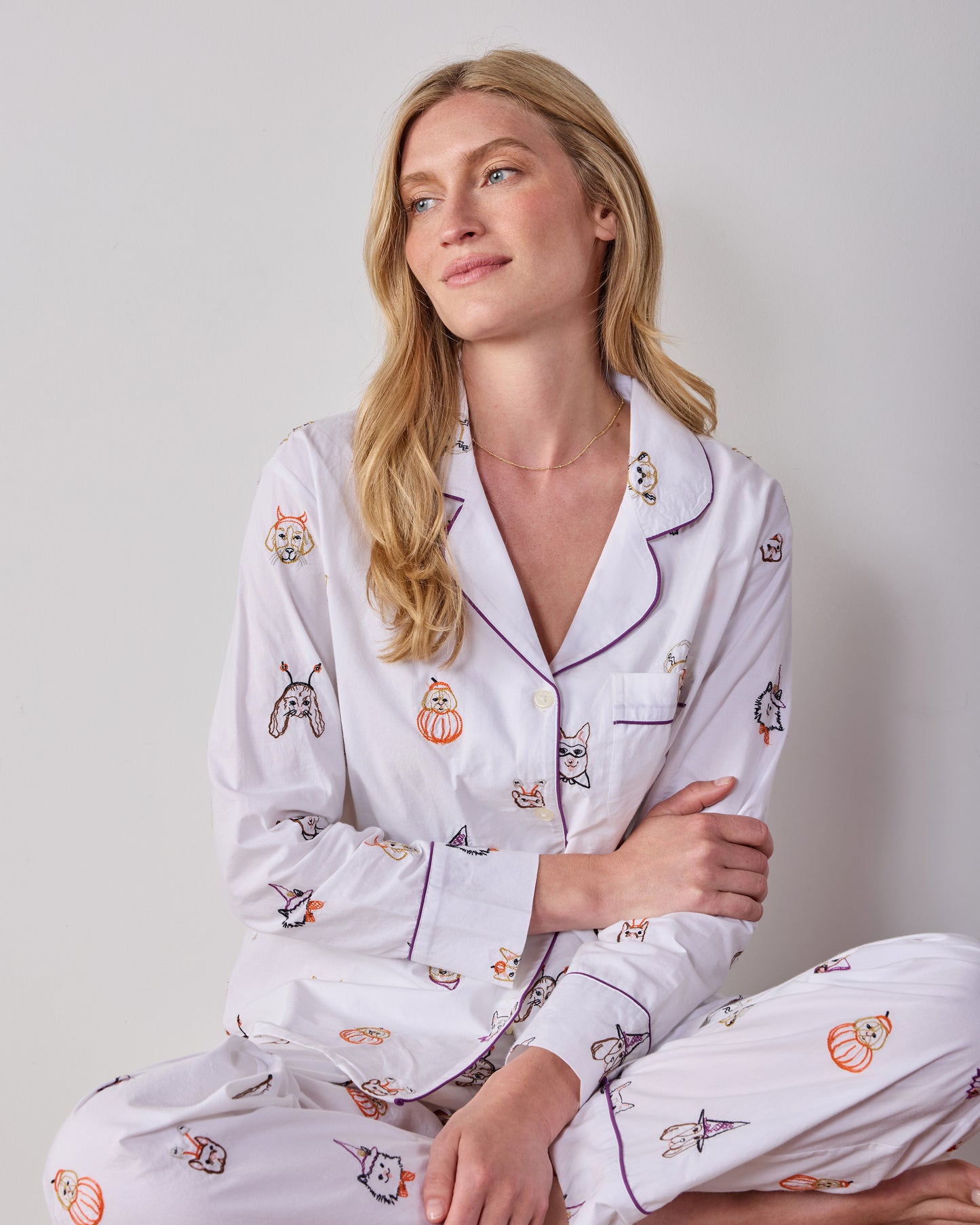 Seated view of the Cloud Halloween Hounds petite long pajama set, showing the piped button-front top and matching printed pants.