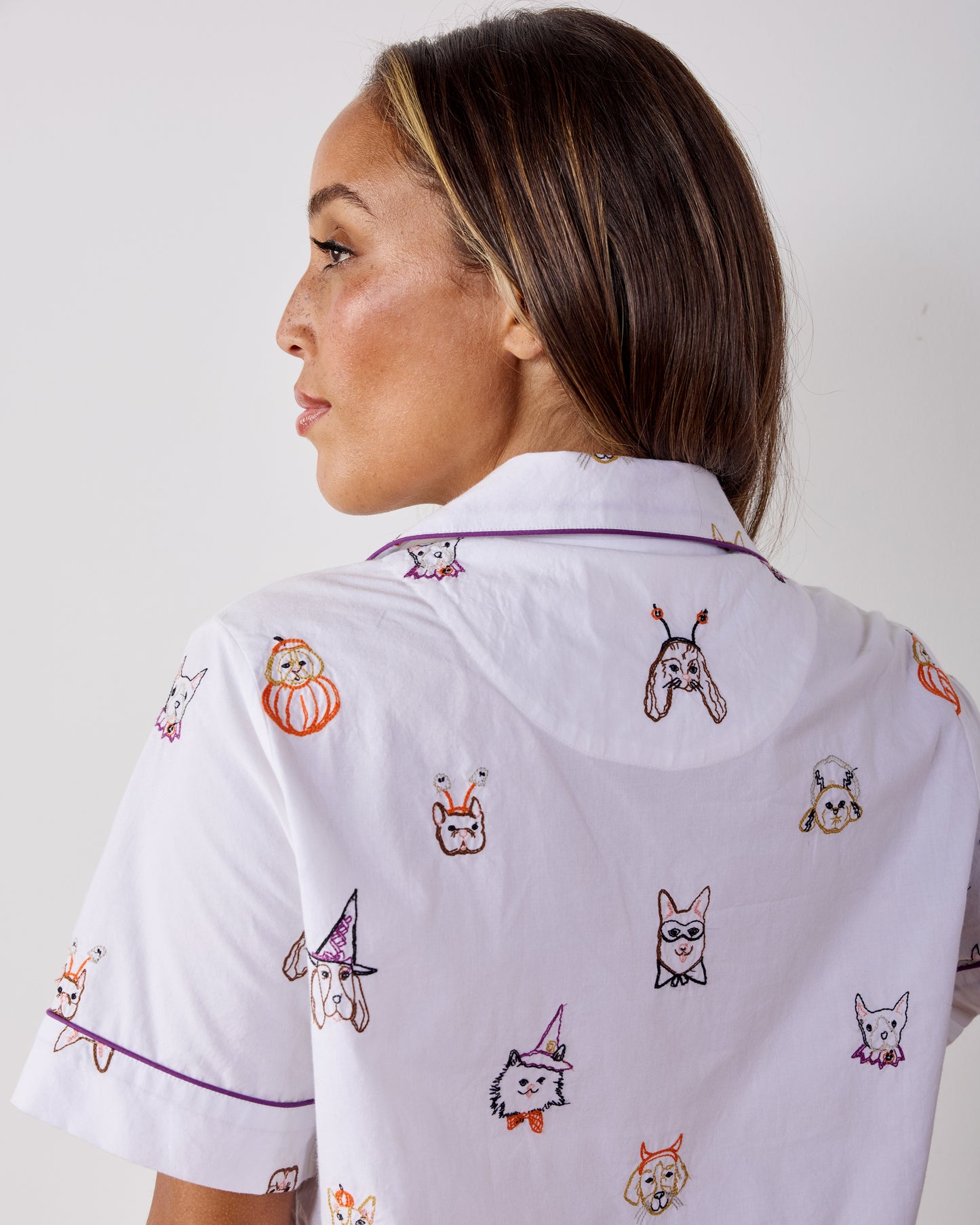 Back view of a person wearing the Halloween Hounds short-sleeve pajama top, showing the dog costume print and purple piping.