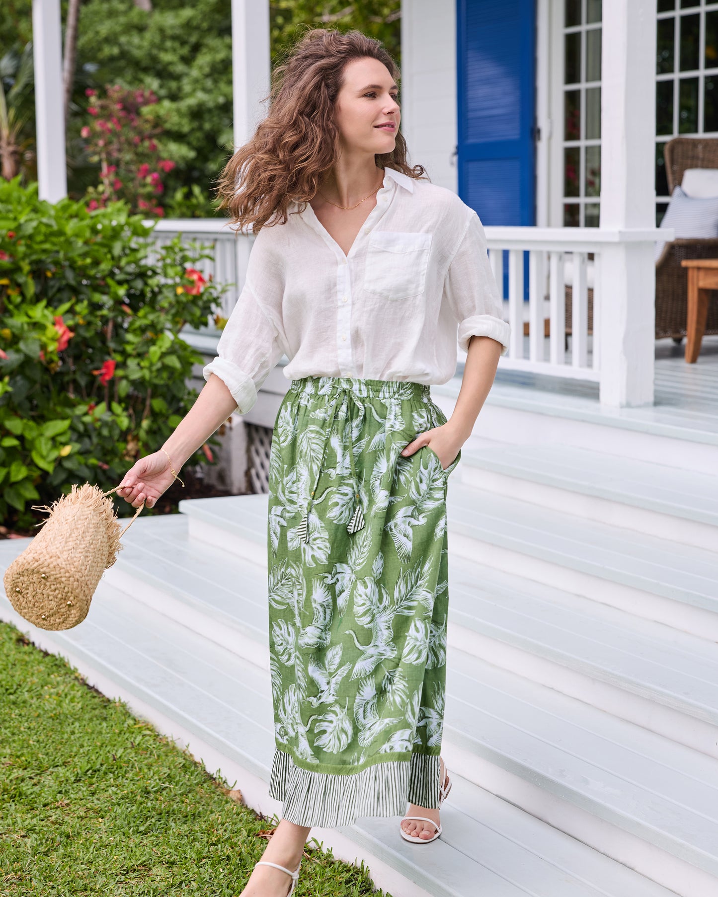 Front view of the olive green Devon Skirt showing the white heron and palm print, drawstring waist, pocket, and striped hem