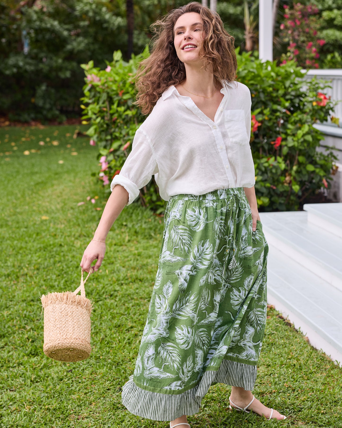 Three-quarter view of the olive green Devon Skirt with white heron and palm print, drawstring waist, and striped hem