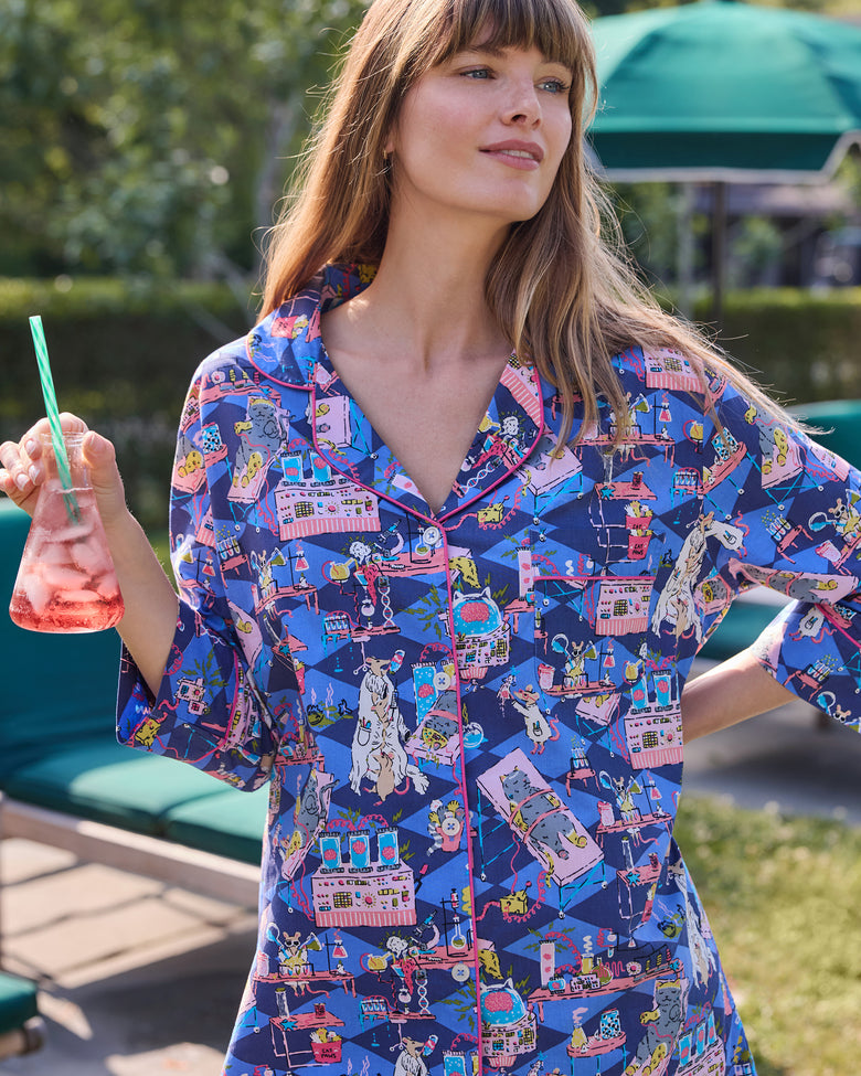 Close view of a blue button-down sleep shirt with a colorful mice-and-laboratory print and contrasting piping.