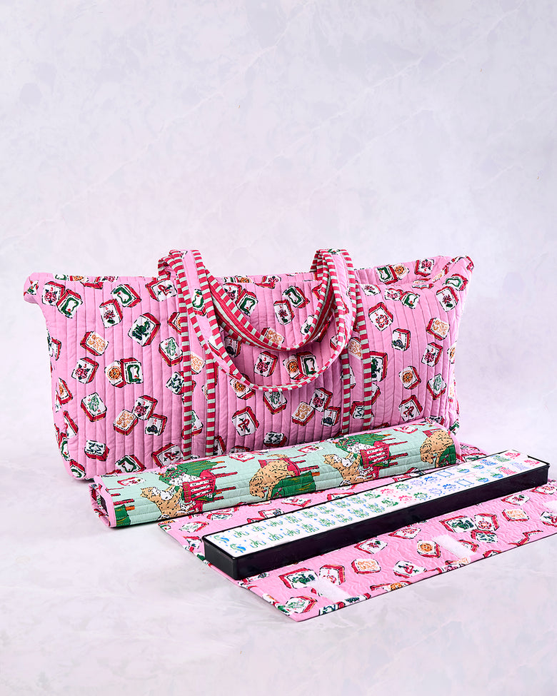 Peony pink quilted Mah Jongg bag with handles and a printed tile pattern, shown with a rolled item, game rack, and mat.