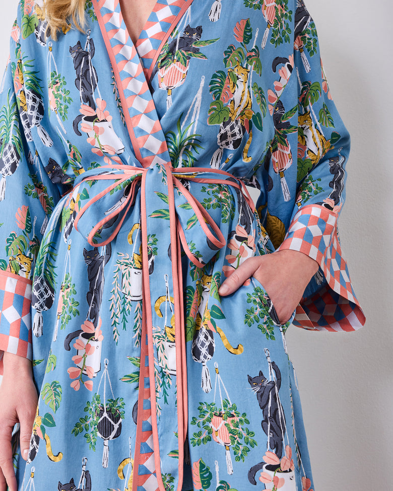 Close-up of the robe's tied belt, pocket, cat-and-houseplant print, and patterned cuffs