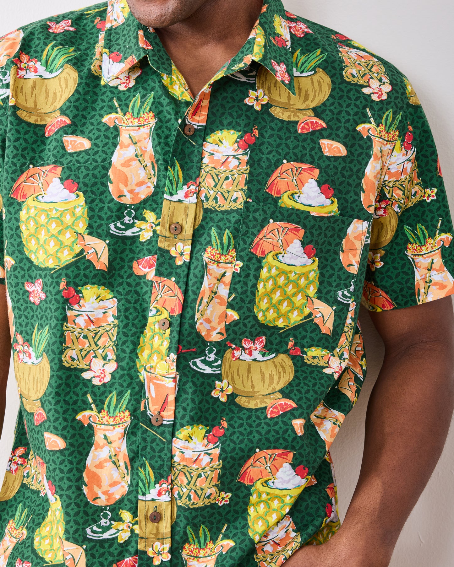 Close-up of the emerald green tropical drink-print shirt's collar, buttons, chest pocket, and short sleeve