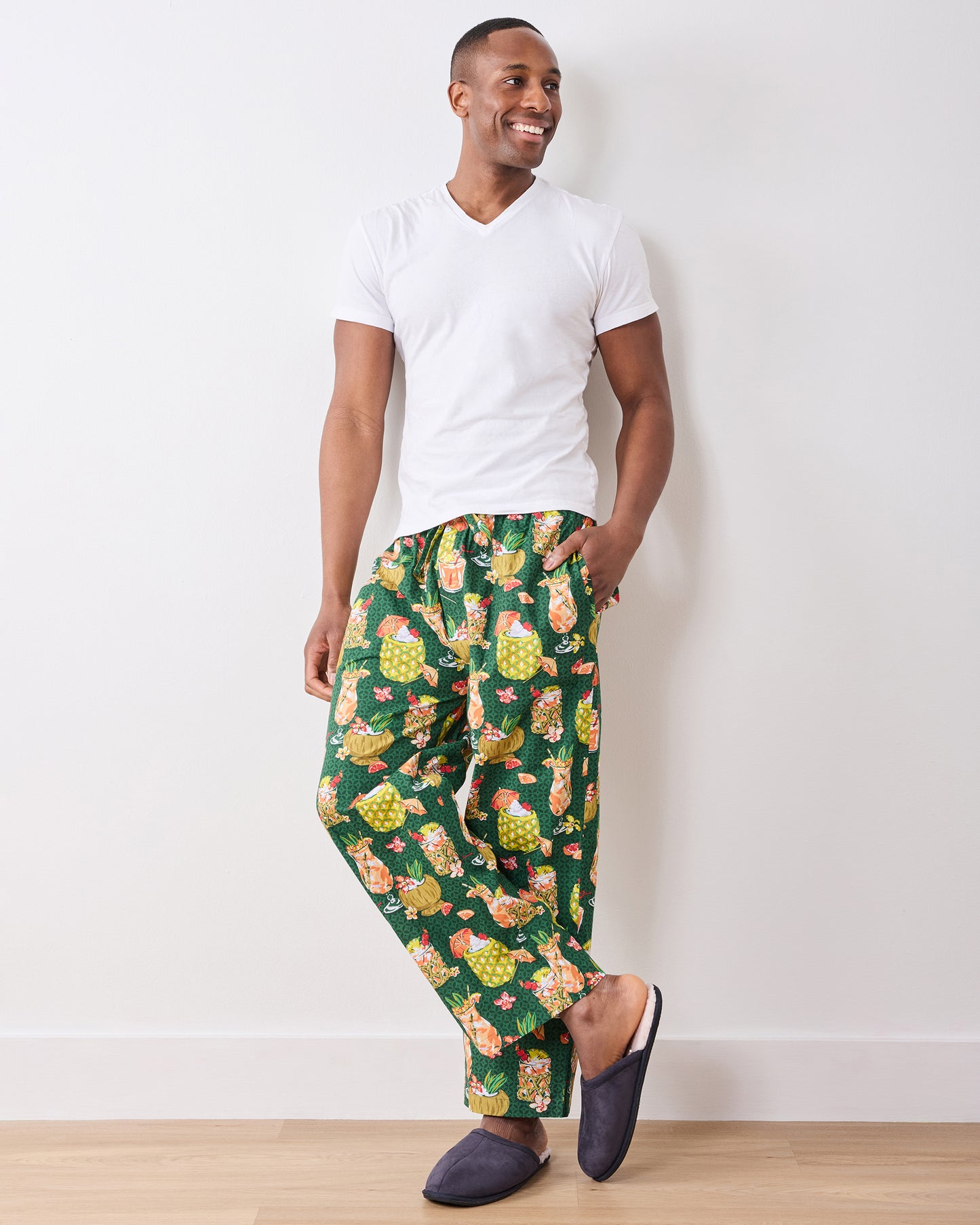 Full-length front view of a model wearing green Paradise Punch pajama pants with slippers