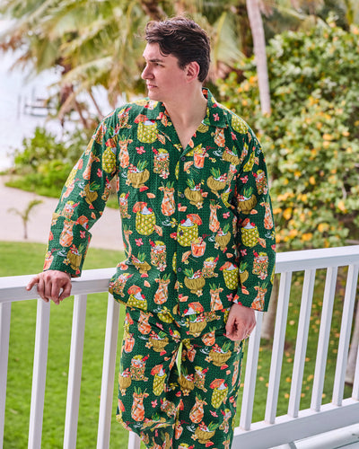 Model wearing the green tropical drink-print long pajama set beside a porch railing