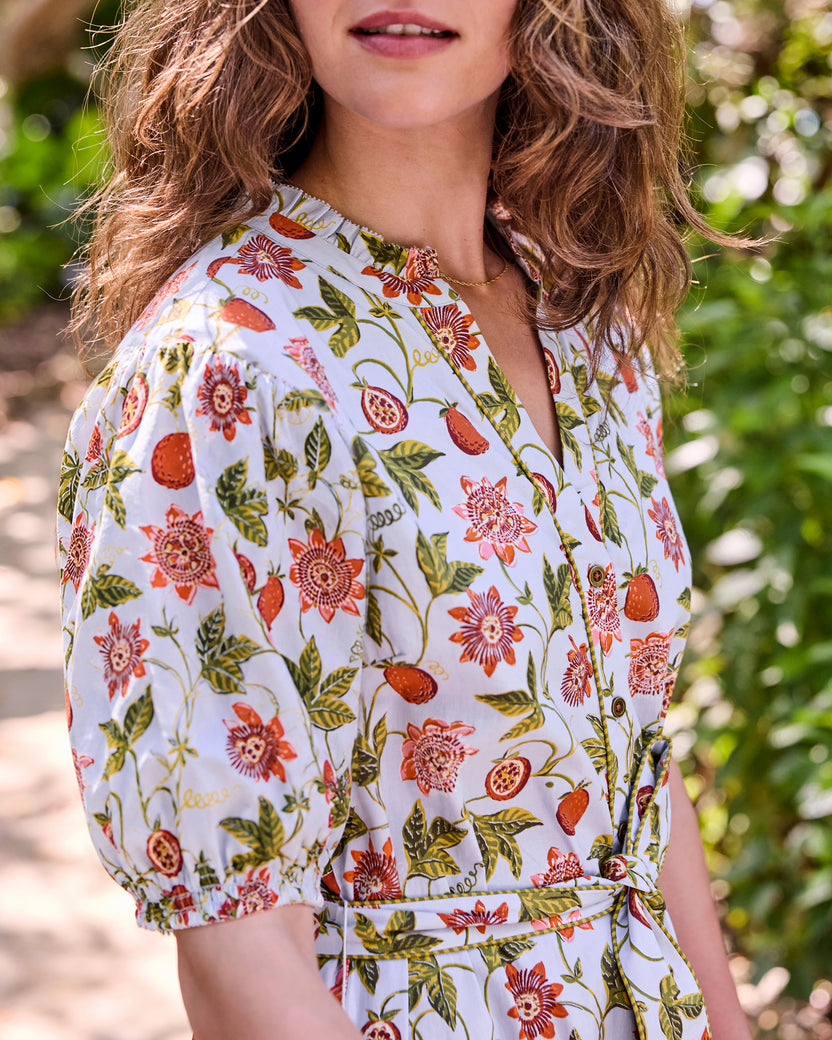 Close view of the light blue Presley dress with a fruit-and-floral print, high collar, button-front opening, puff sleeve, and tie belt.