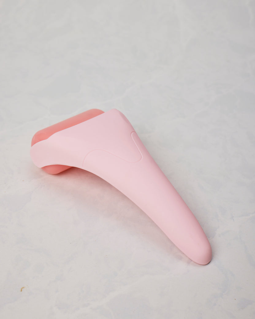 Pink ice roller shown from the back, displaying the tapered handle and rounded roller head.