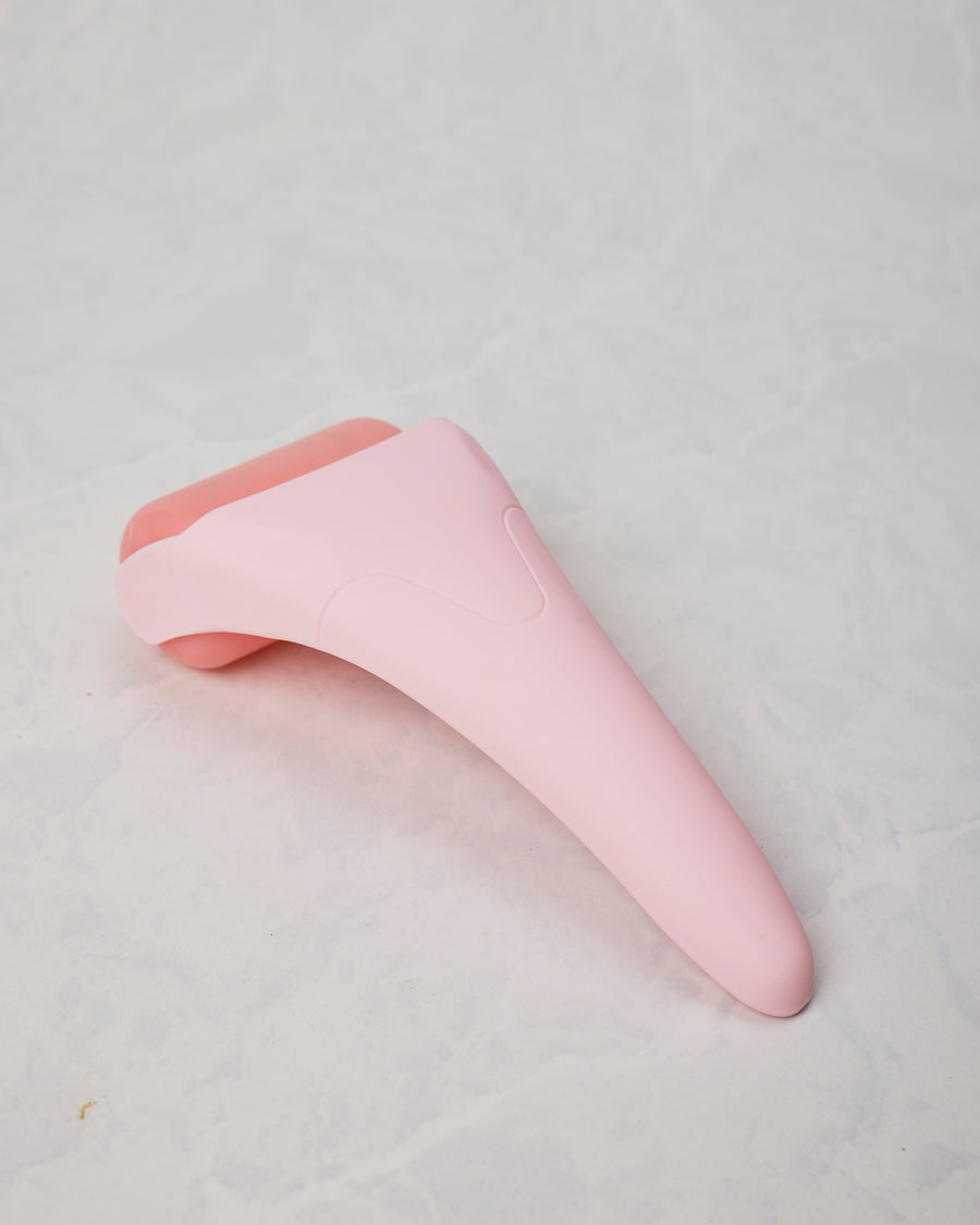 Pink ice roller shown from the back, displaying the tapered handle and rounded roller head.