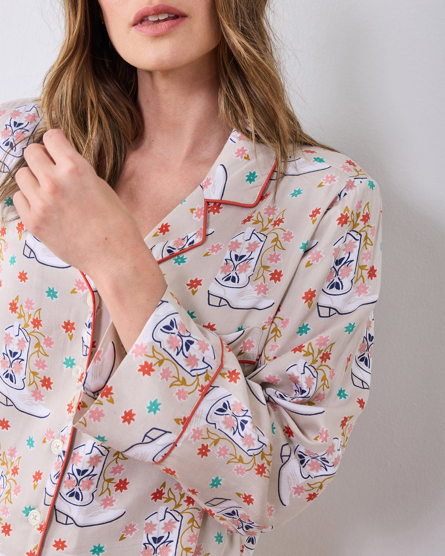 Close-up of the pajama top showing the notched collar, red piping, button front, and printed cuff.