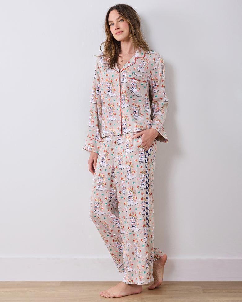Model standing barefoot in a printed long-sleeve pajama top and matching wide-leg pants with contrasting side panels.