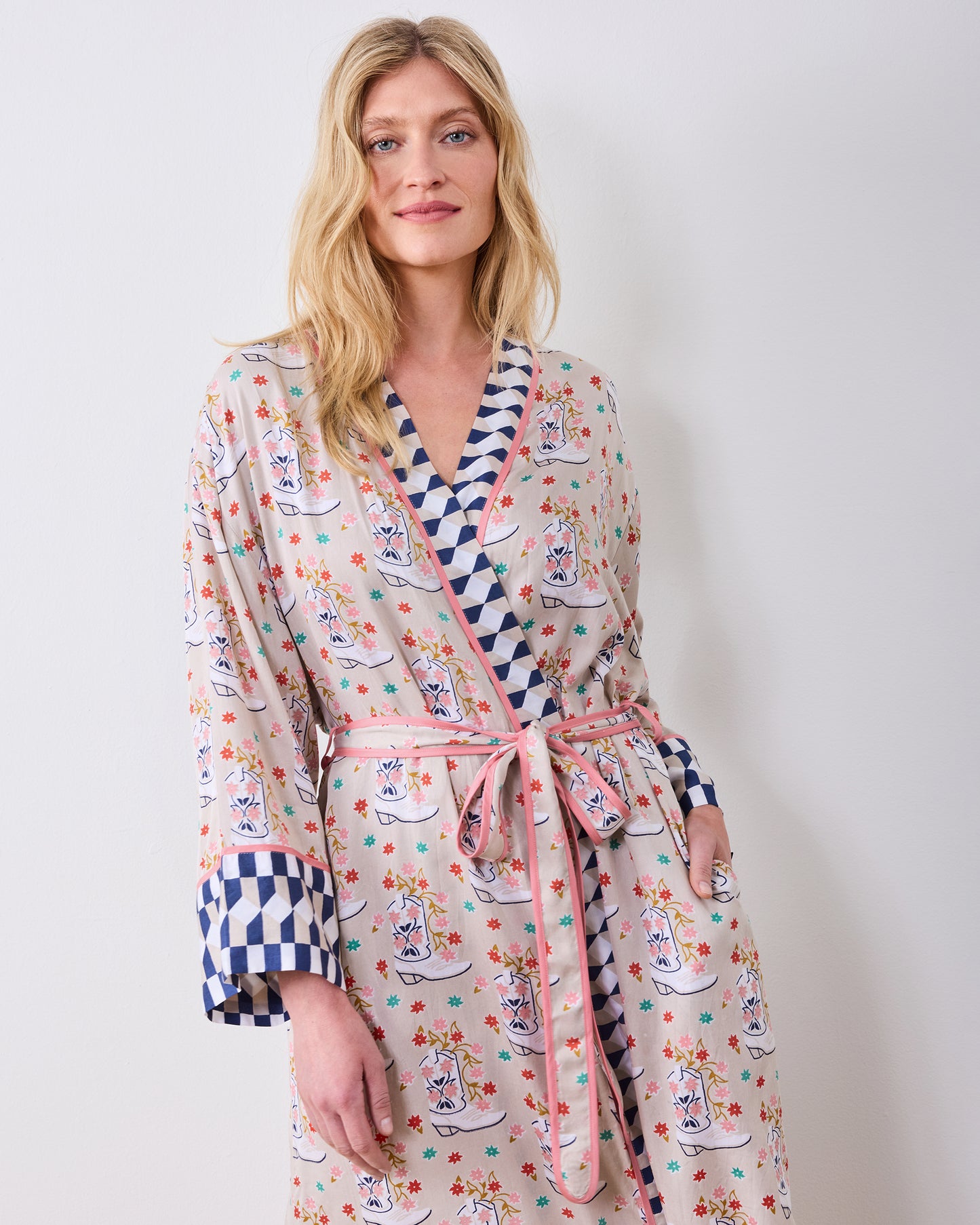 Model wearing a printed robe with a tied belt, pink edging, and blue-and-white checkerboard trim.