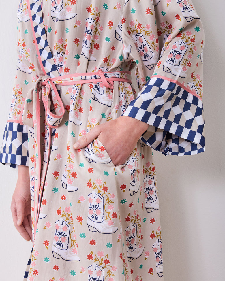 Close-up of a printed robe showing a front pocket, tied belt, and contrasting blue-and-white checkerboard cuffs.