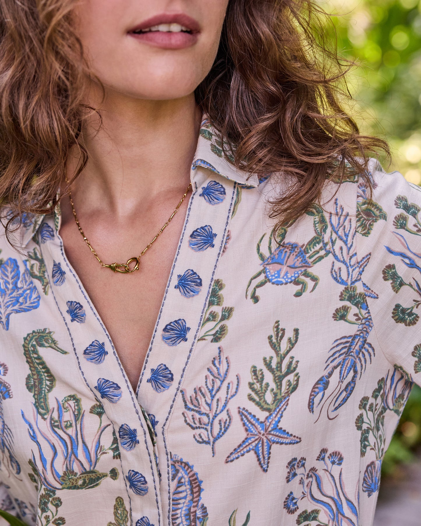 Close-up of the sand-colored Goa Dress neckline and blue-and-green sea-life print, including shells, crab, lobster, starfish, and seahorse motifs