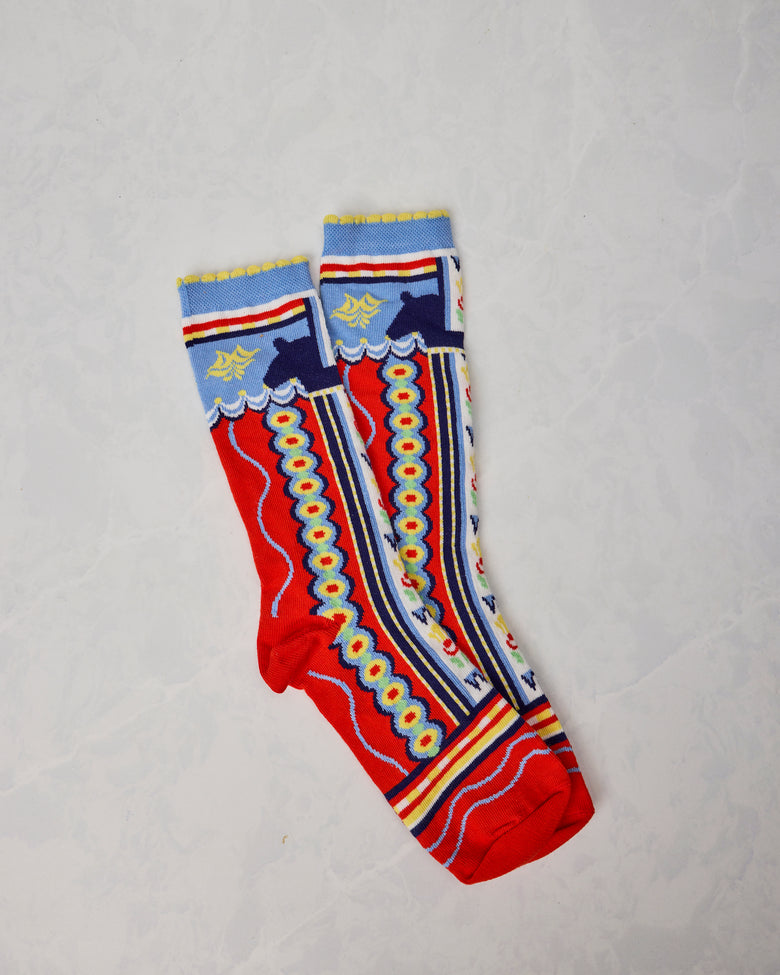 Pair of colorful Dala Horse socks overlapping on a light background, showing red, blue, yellow, and white patterned designs.