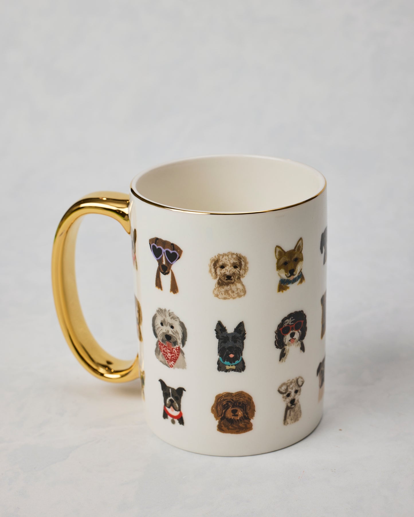 Dog Days porcelain mug shown from an angled view with a gold handle and rows of illustrated dogs wearing accessories.