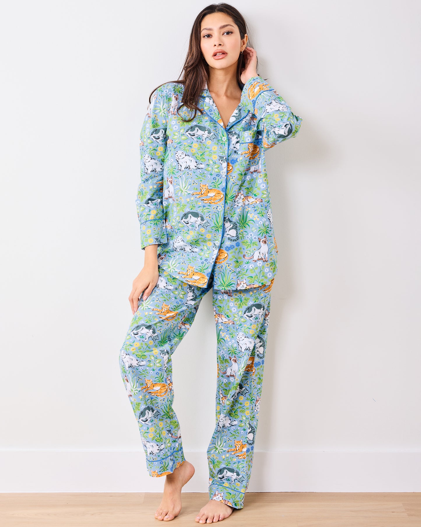 Full front view of a model wearing the blue long pajama set with cats, flowers, and greenery