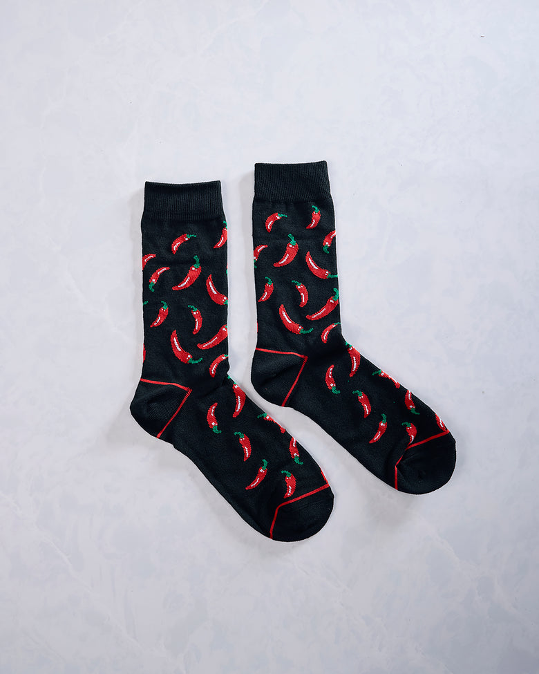 Pair of black socks with repeating red chili pepper designs and red seam details.