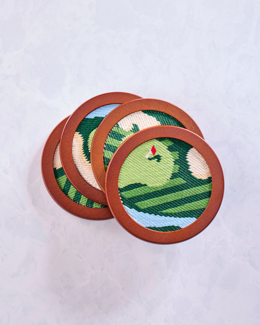 Four overlapping round green stitched golf coasters showing varied sections of the golf-themed designs.