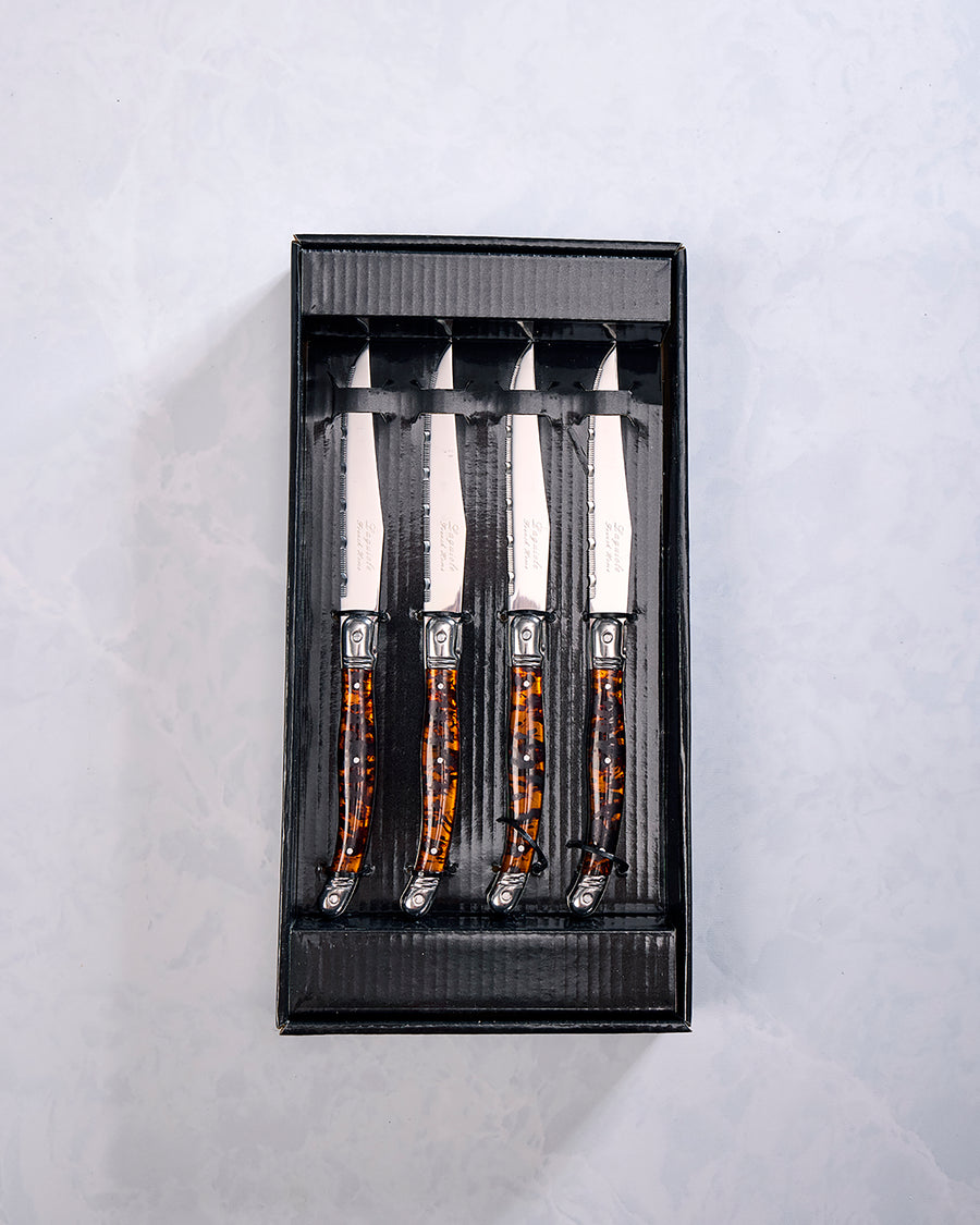 Four Laguiole steak knives with tortoise shell-style handles displayed in a black presentation box.