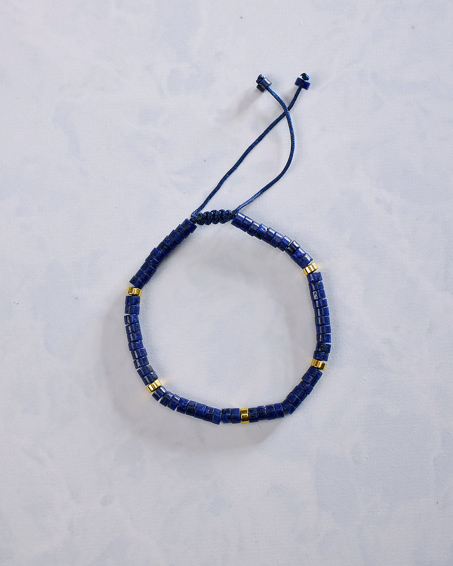 Blue beaded bracelet arranged in an oval, with small gold-tone accent beads and an adjustable cord closure.