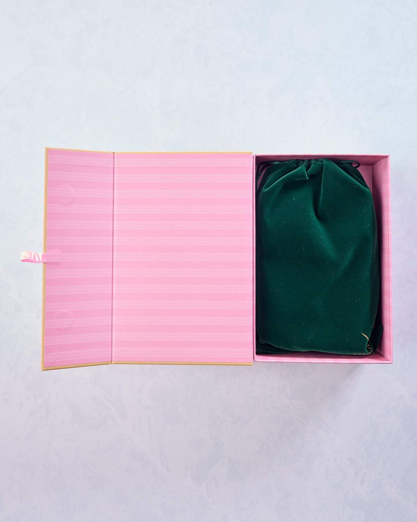 Open pink puzzle box containing a green velvet storage bag.