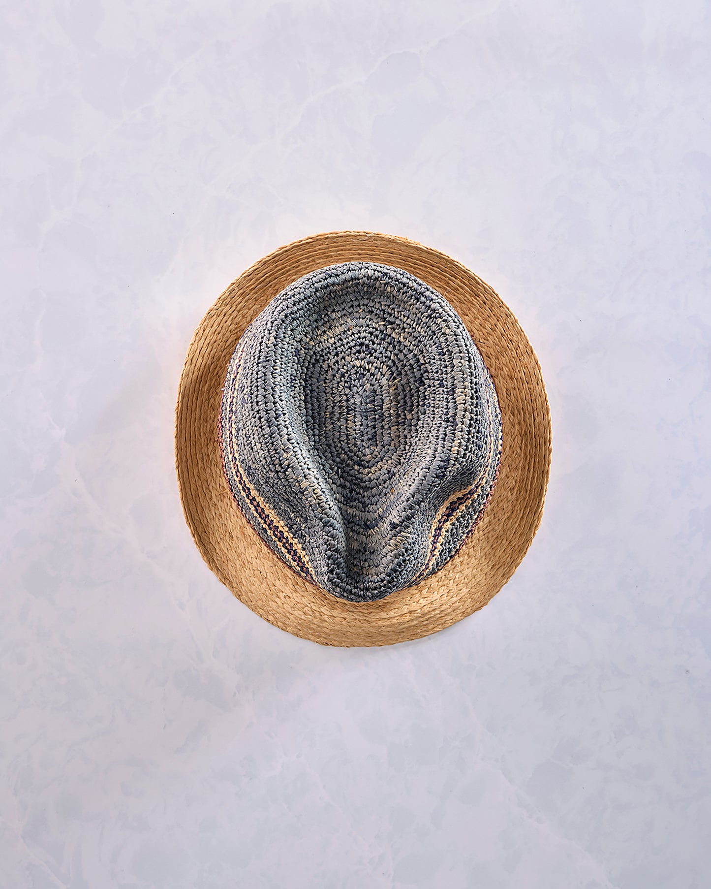 Top view of a crocheted fedora with a natural-colored brim and a blue-gray striped crown.