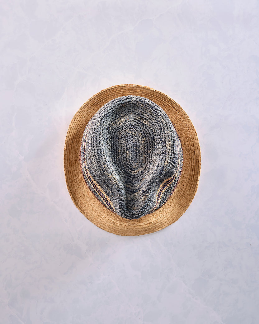 Top view of a crocheted fedora with a natural-colored brim and a blue-gray striped crown.