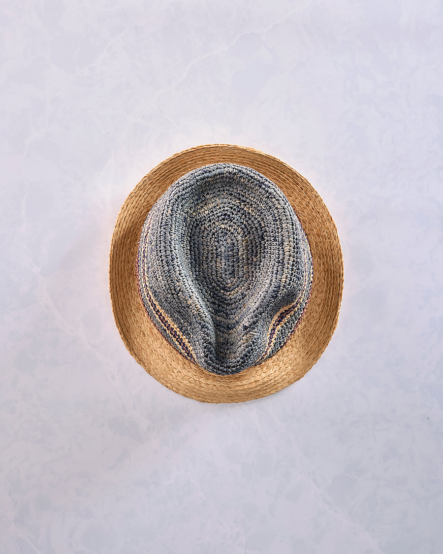 Top view of a crocheted fedora with a natural-colored brim and a blue-gray striped crown.