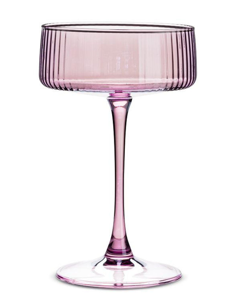 Single pink ribbed cocktail coupe glass with a long stem and round base.