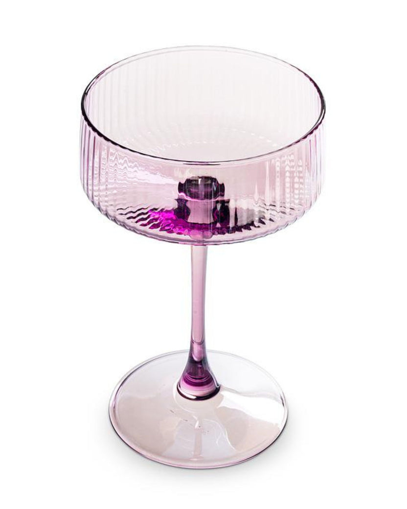 Angled view of a pink ribbed cocktail coupe glass showing the open bowl, stem, and round base.
