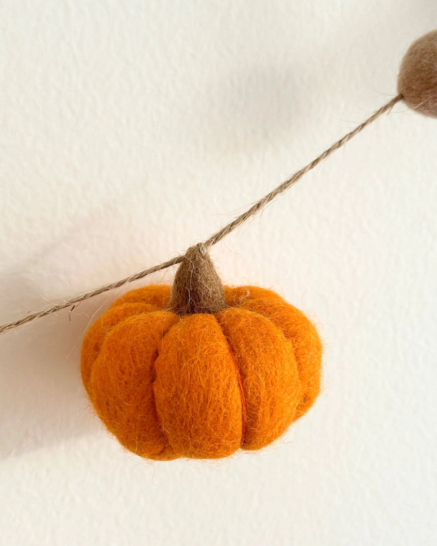 Close-up of an orange pumpkin ornament attached to the garland string.