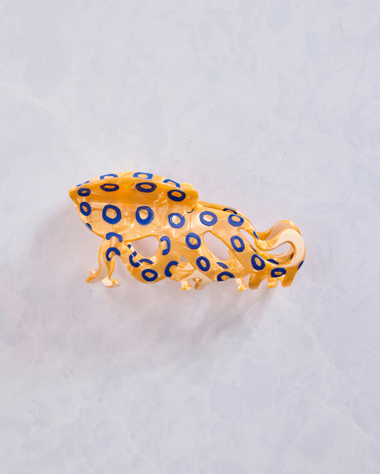 Side view of the orange translucent octopus-shaped claw clip with blue ring markings.