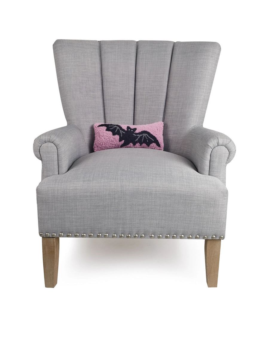 Gray wingback chair displaying the pink bat accent pillow.
