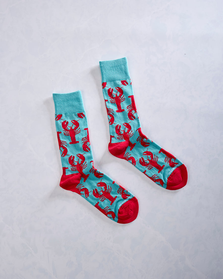Pair of turquoise socks with repeating red lobster designs and red toes and heels.