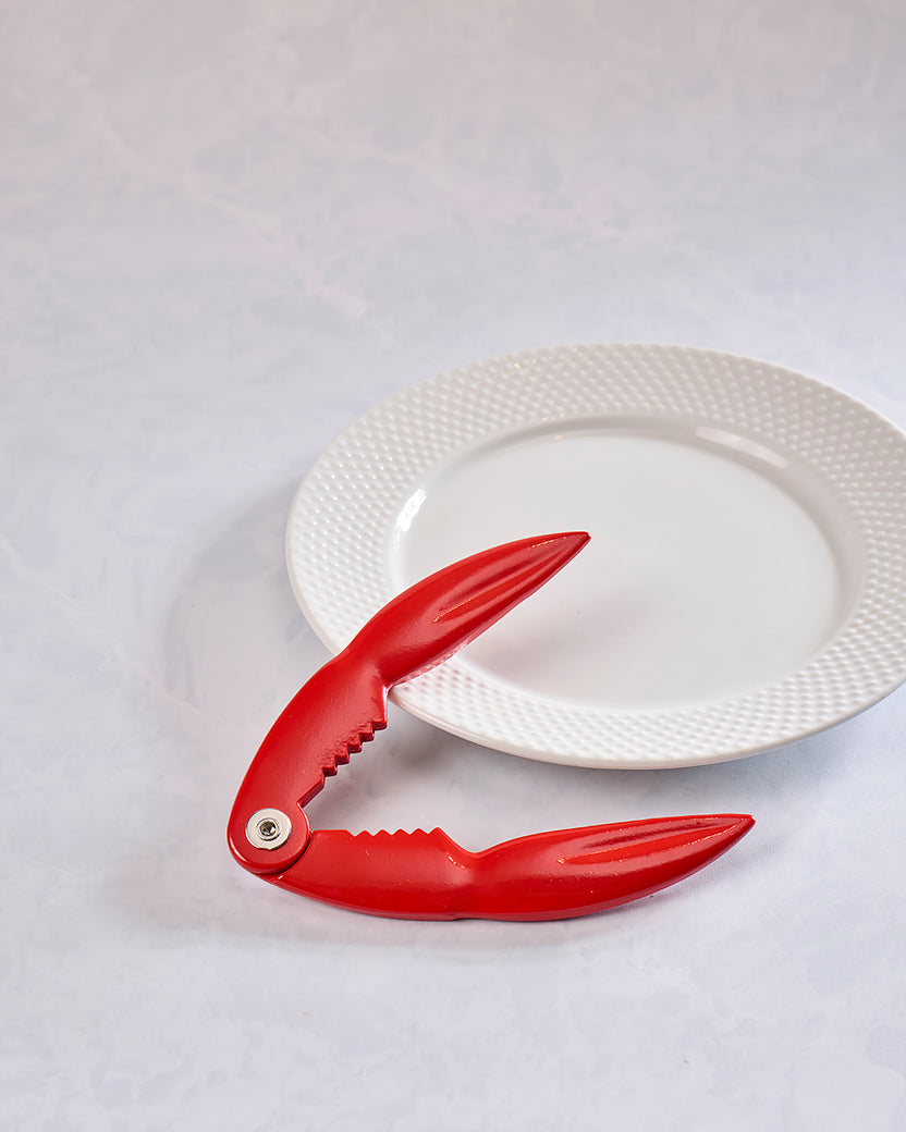 Red lobster claw cracker beside a white plate