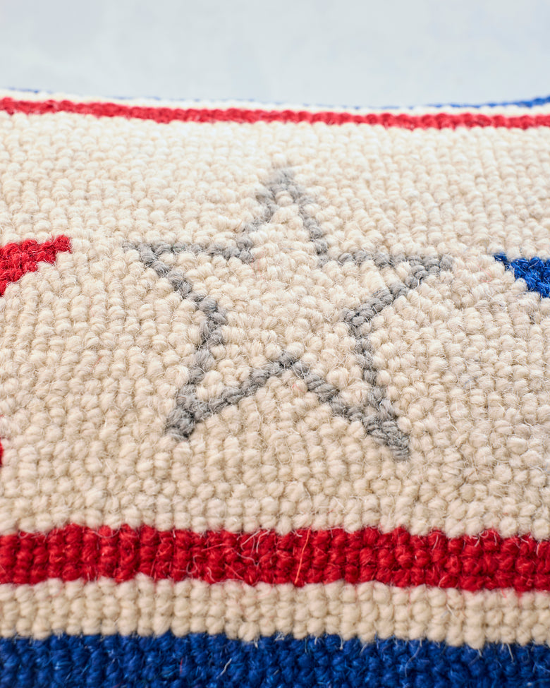 Close-up of the Americana pillow’s hooked front, showing cream fabric, red and blue stripes, and a gray outlined star.