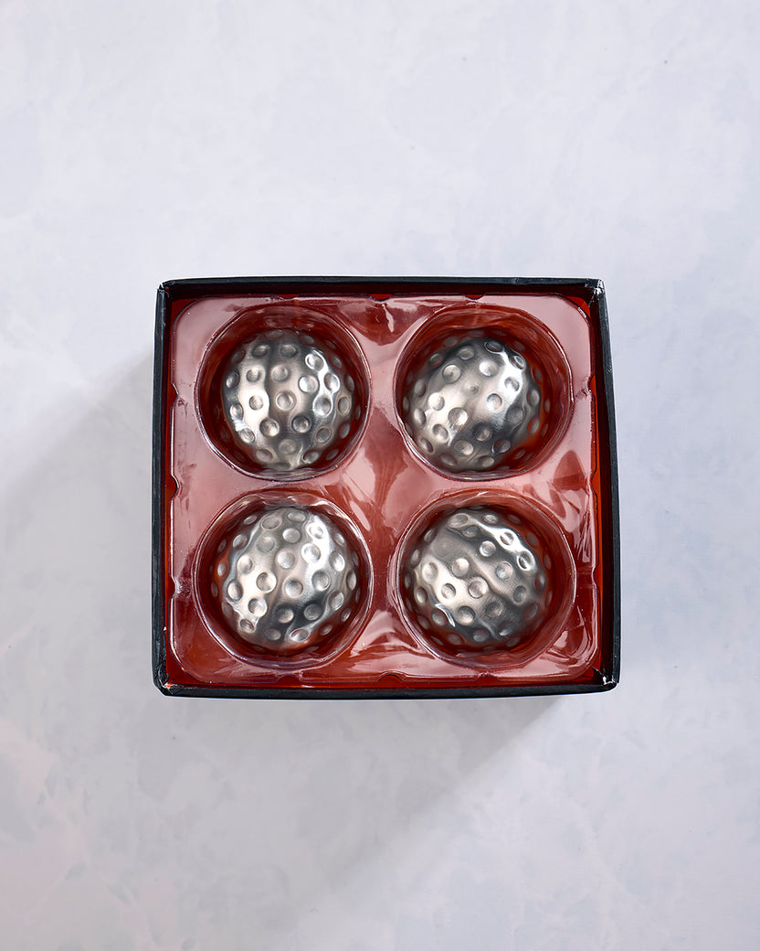 Open package containing four silver dimpled metal chilling cubes in a red tray.