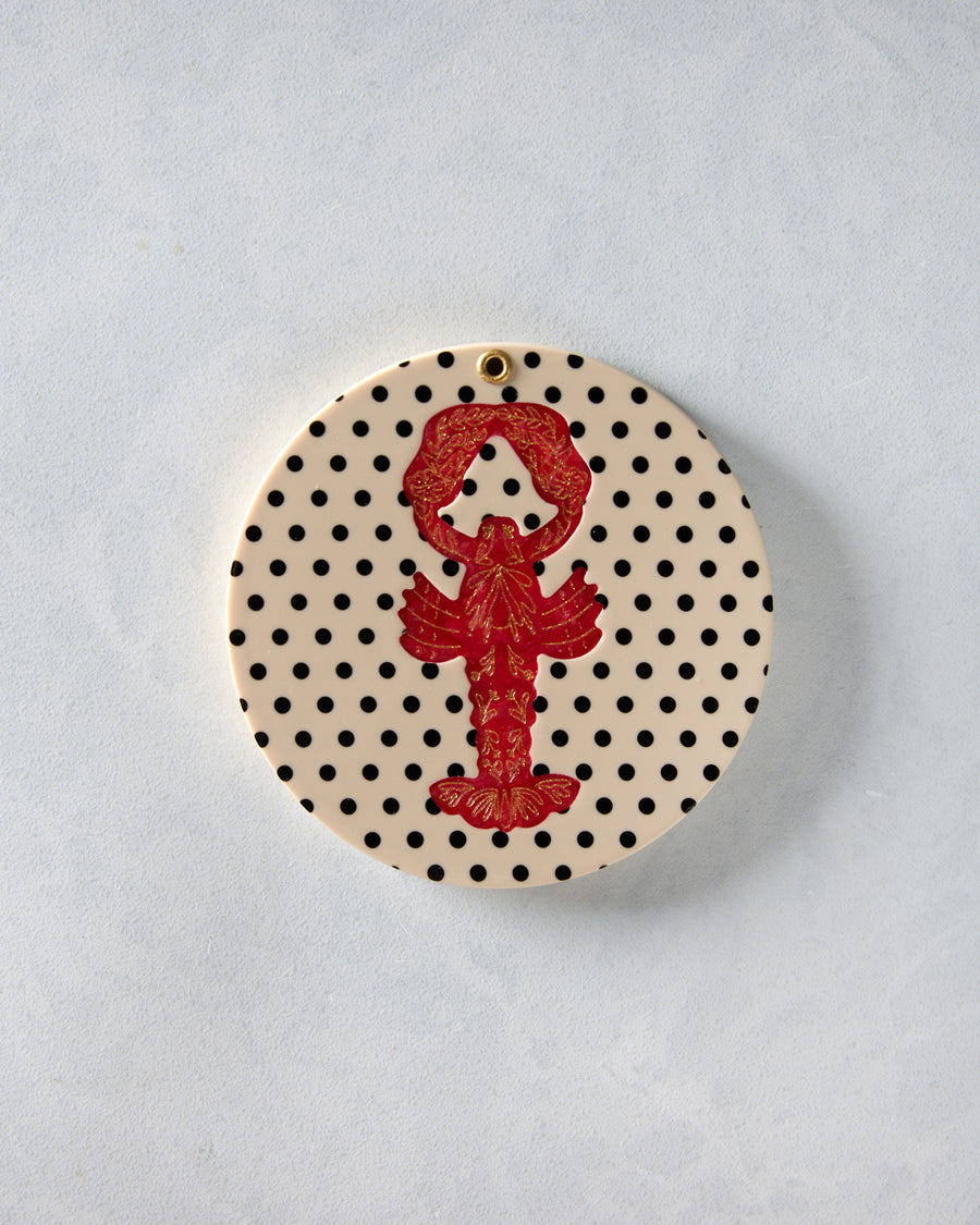 Closed round compact mirror with a cream cover, black polka dots, and a red lobster design.