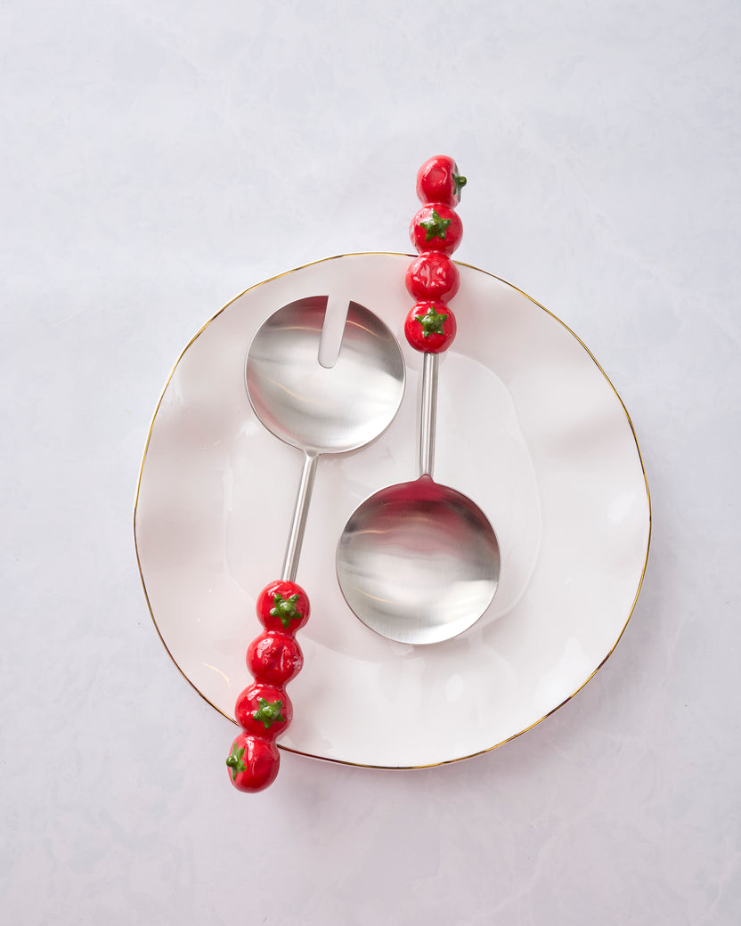 Tomato-handle salad servers arranged across a round plate