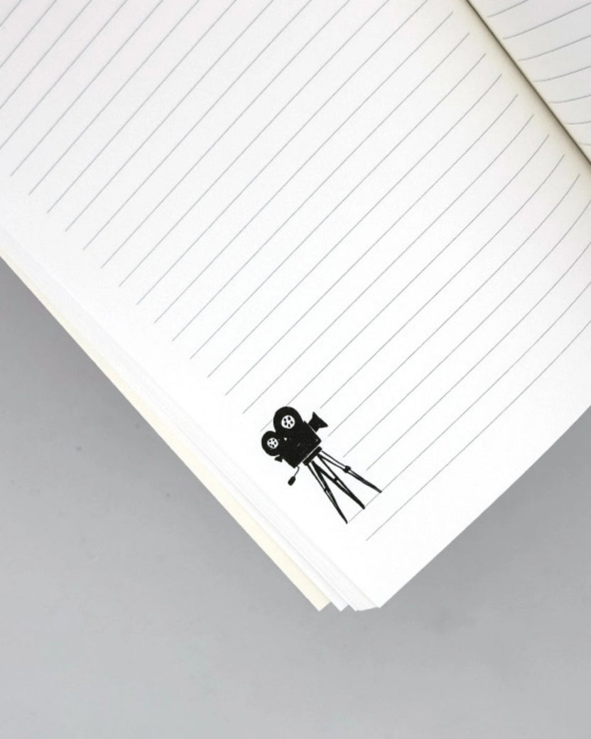 Lined journal page with a black movie-camera illustration near the bottom